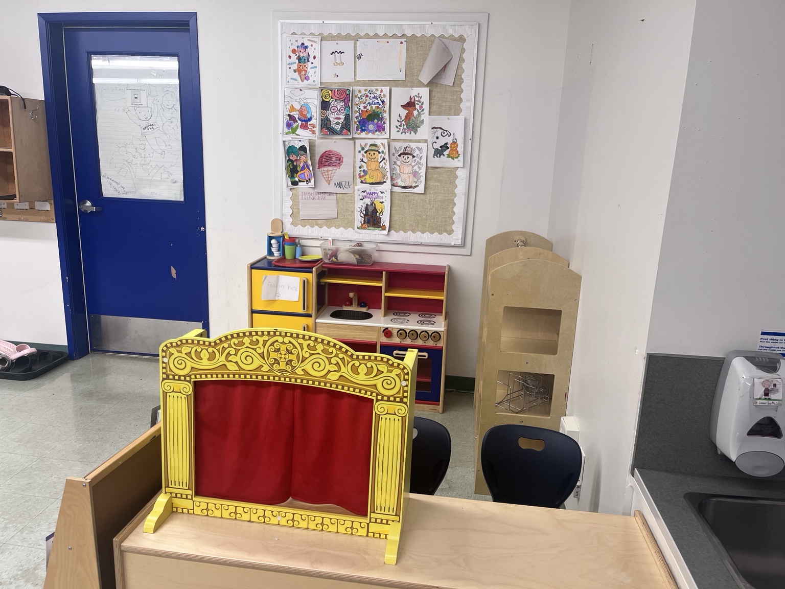 A small red-and-gold puppet theatre in a classroom dramatic-play area