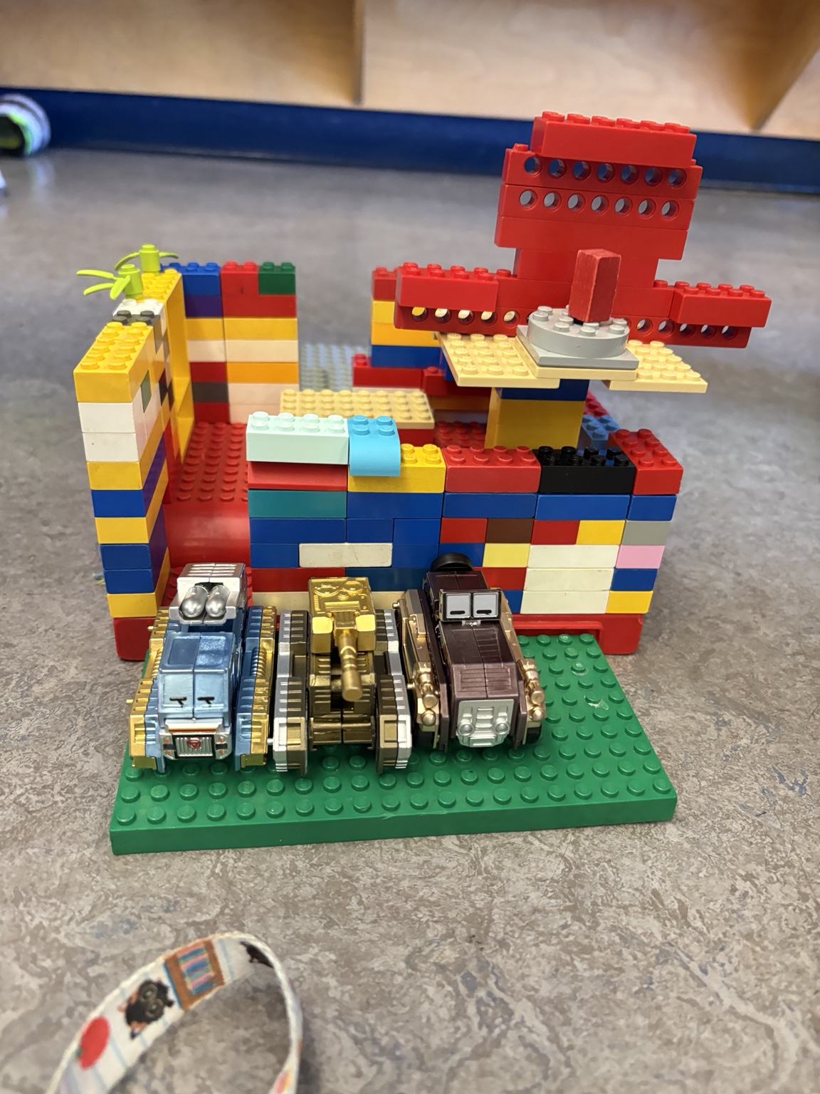 A colourful LEGO structure with vehicles arranged on a green baseplate